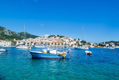 Boats moored at harbor against blue sky