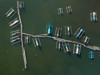 Directly above shot of outrigger canoes moored at pier on sea