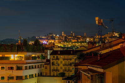 Illuminated cityscape against sky at night