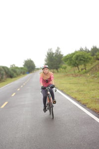 Asian woman cycling on a straight road close to the beach