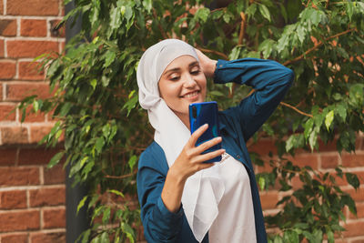 Woman taking selfie while standing outdoors