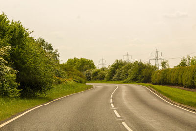 Empty road amidst trees against sky