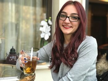 Portrait of a smiling young woman drinking glasses outdoors