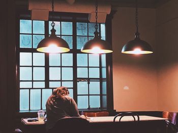 Rear view of studying in illuminated room