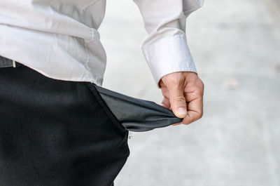 Midsection of man holding empty pocket on road