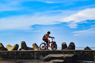 Boy riding bicycle against sky