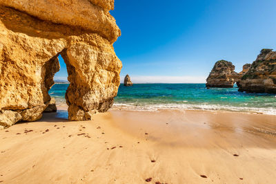 View of rocks on beach against blue sky