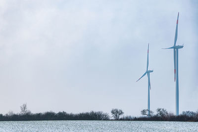 Wind turbines on landscape against sky