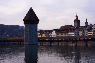 Bridge over river by buildings against sky in city