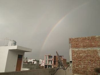 Low angle view of rainbow over building against sky