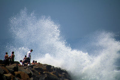 High angle view of waves splashing in sea against clear sky