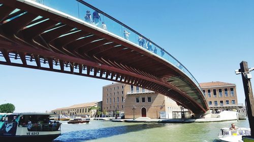 Bridge over river in city against clear sky