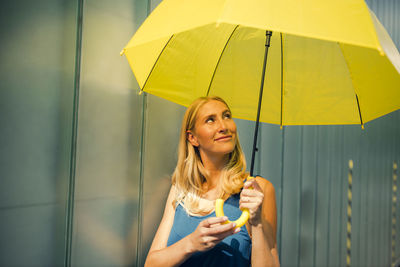 Young woman looking away while standing in rain