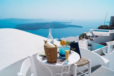 Chairs and table by sea against sky