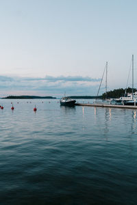 Sailboats in sea against clear sky