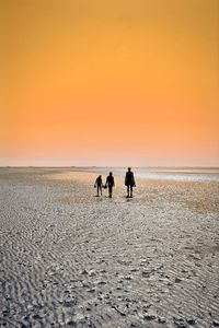 People on beach against sky during sunset