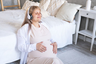 Pregnant woman with big belly advanced pregnancy in wireless headphone listening music
