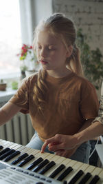 Girl learning piano with teacher