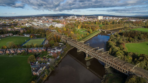 High angle view of bridge over lake and trees against cloudy sky