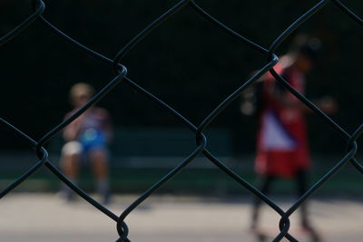 People seen through chainlink fence 