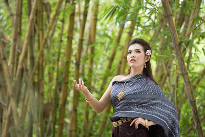 Portrait of young woman standing against plants