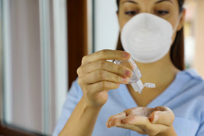 Young woman using hand sanitizer at home