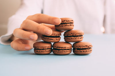 Midsection of woman stacking macaroons on table 