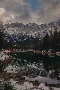 Scenic view of lake by snowcapped mountains against sky