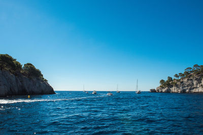 Sailboats sailing in sea against clear blue sky