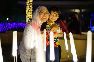 Portrait of mother with son standing in illuminated room