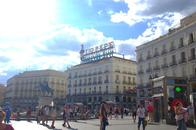 People walking in town square against sky