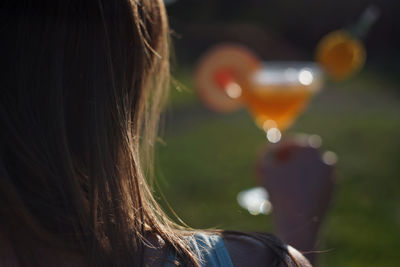 Woman holding orange peach cocktail in glass with ice cubes and straw