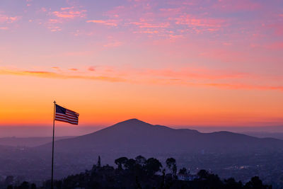 Silhouette flag against orange sky