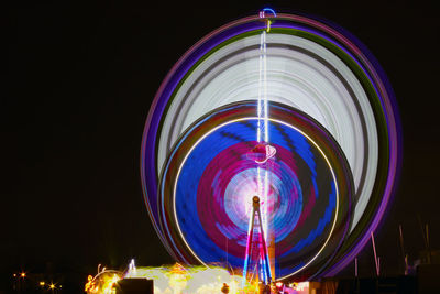 Low angle view of illuminated ferris wheel against sky at night