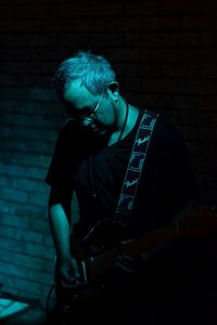 Man playing guitar against wall
