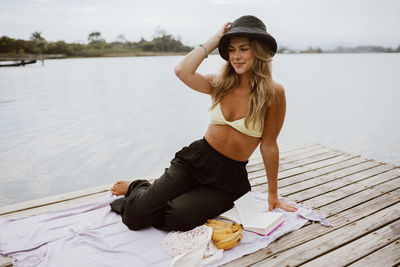 Portrait of young woman sitting on pier