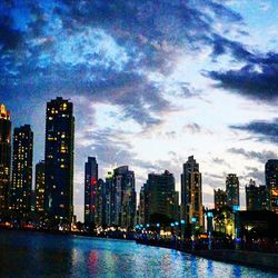 Illuminated buildings in city against sky at dusk