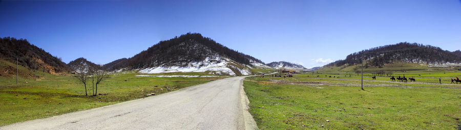 Empty road amidst field against clear sky