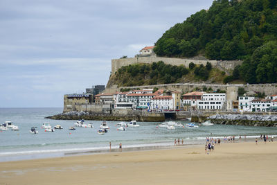 People on beach by sea against sky