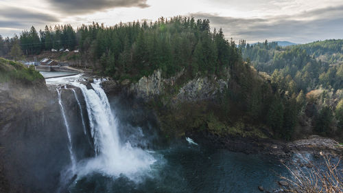 Scenic view of waterfall in forest against sky