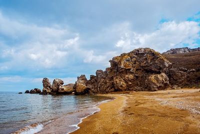 Rock formation on beach against sky