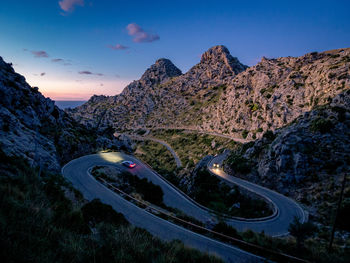 Cars on road by mountain against sky