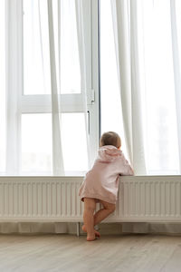 Rear view of woman looking through window