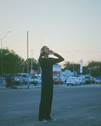 Rear view of man standing on road against clear sky