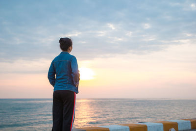 Rear view of man looking at sea against sky