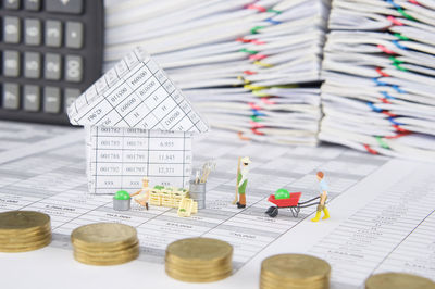 Close-up of coins with manual worker figurines and files on financial documents