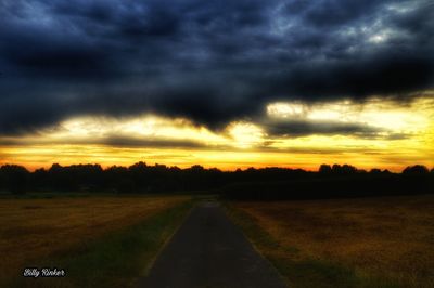 Scenic view of road against dramatic sky during sunset