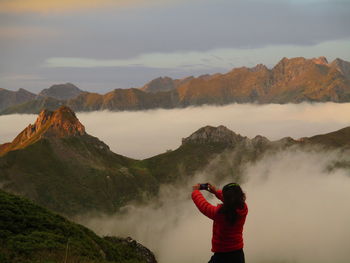 Rear view of man photographing against mountain range