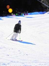 Rear view of boy skiing on snowy field