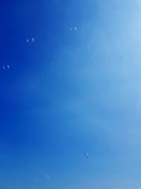 Low angle view of bubbles in blue sky